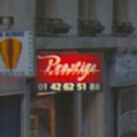 Close-up of a red shop sign reading Prestige, with a phone number beneath it.
